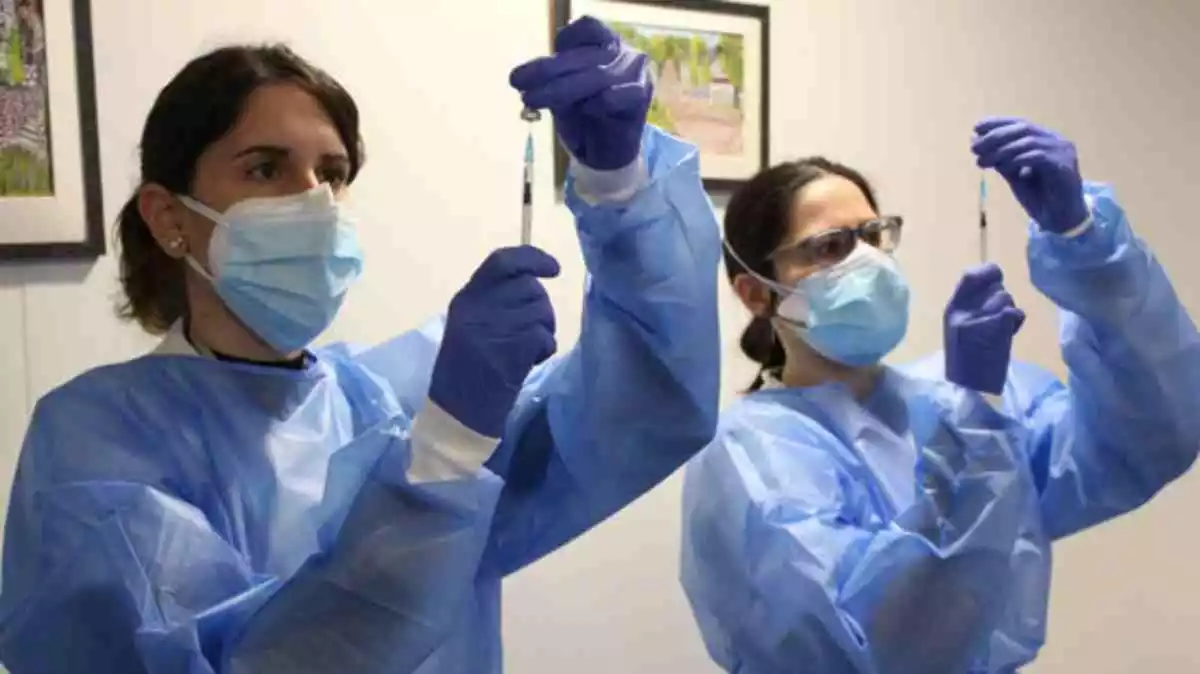 Pla conjunt de dues infermeres preparant les dosis de la vacuna contra la covid-19 en la campanya de vacunació de la segona dosi