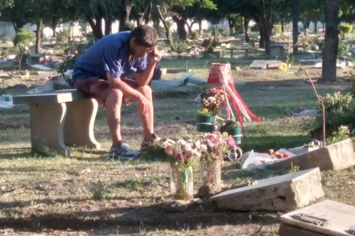 Un padre junto a la tumba de su hijo
