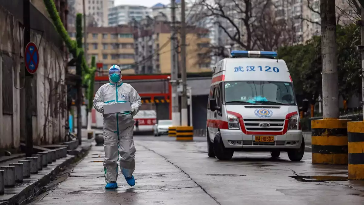 Imagen de una ambulancia china y un especialista con traje y mascarilla