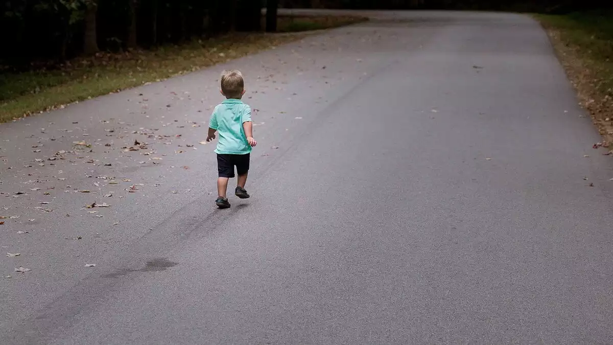 Imagen de archivo de un niño pequeño caminando por una carretera