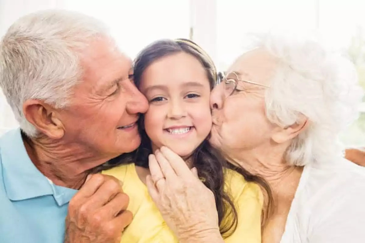 Imagen de dos abuelos besando a su nieta