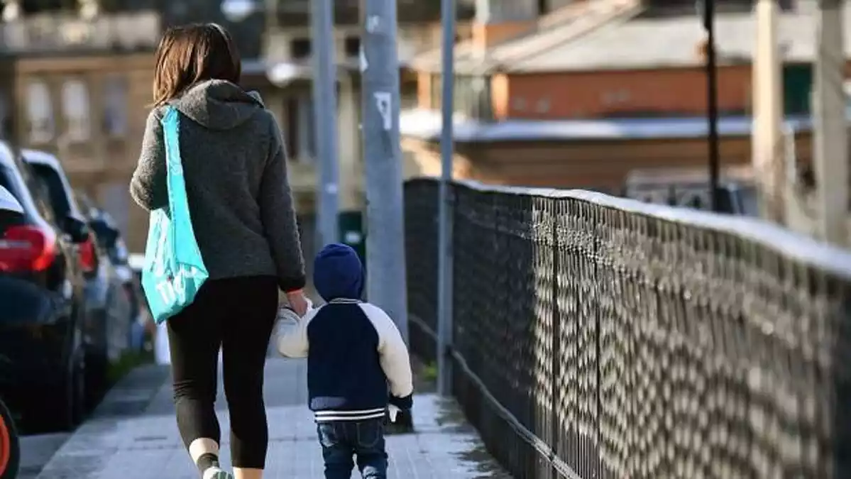 Una madre acompaña a su hijo pequeño por la calle