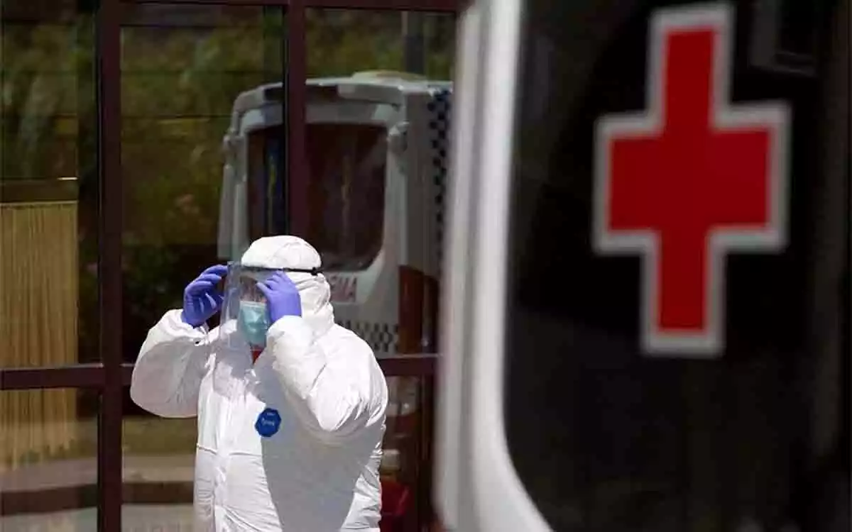 Sanitario con mascarilla junto a un vehículo de la Cruz Roja