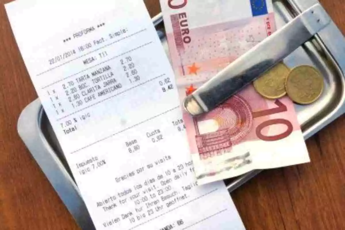Plano de detalle de una cuenta con un billete y monedas de euro al lado en un restaurante