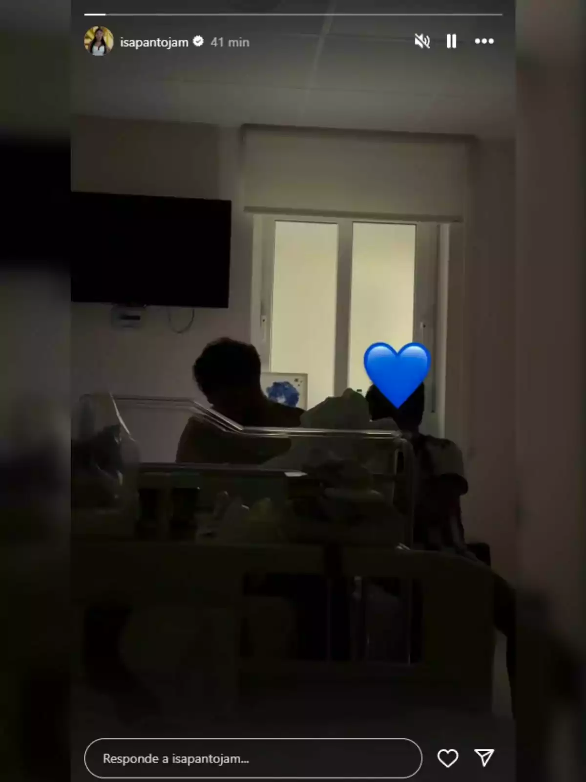 Habitació d’hospital amb dues persones assegudes al costat d’un bressol —una d’elles és l’Asraf Beno— i un cor blau cobrint la cara d’una d’elles. Habitació d’hospital amb dues persones assegudes al costat d’un bressol —una d’elles és l’Asraf Beno— i un cor blau cobrint la cara d’una d’elles.