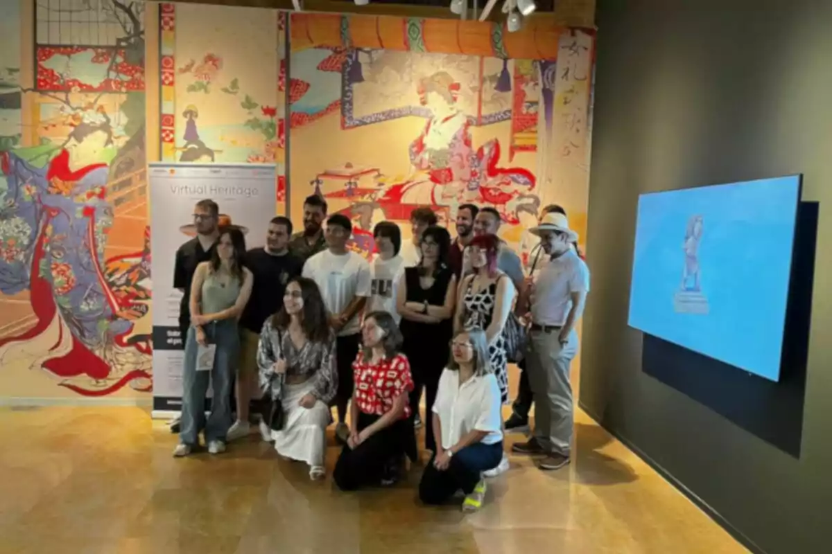 Grup de persones posant en una exposició amb murals d’art japonès i una pantalla encesa a la paret Grup de persones posant en una exposició amb murals d’art japonès i una pantalla encesa a la paret