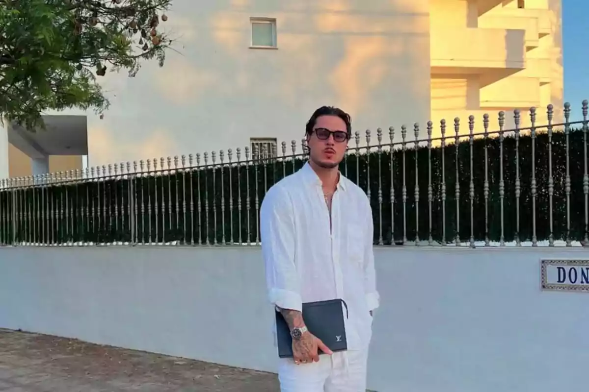 Carlo Costanzia vestit amb camisa i pantalons blancs posant al carrer al costat d’una reixa metàl·lica i un edifici al fons, sostenint una carpeta negra i portant ulleres de sol. Carlo Costanzia vestit amb camisa i pantalons blancs posant al carrer al costat d’una reixa metàl·lica i un edifici al fons, sostenint una carpeta negra i portant ulleres de sol.