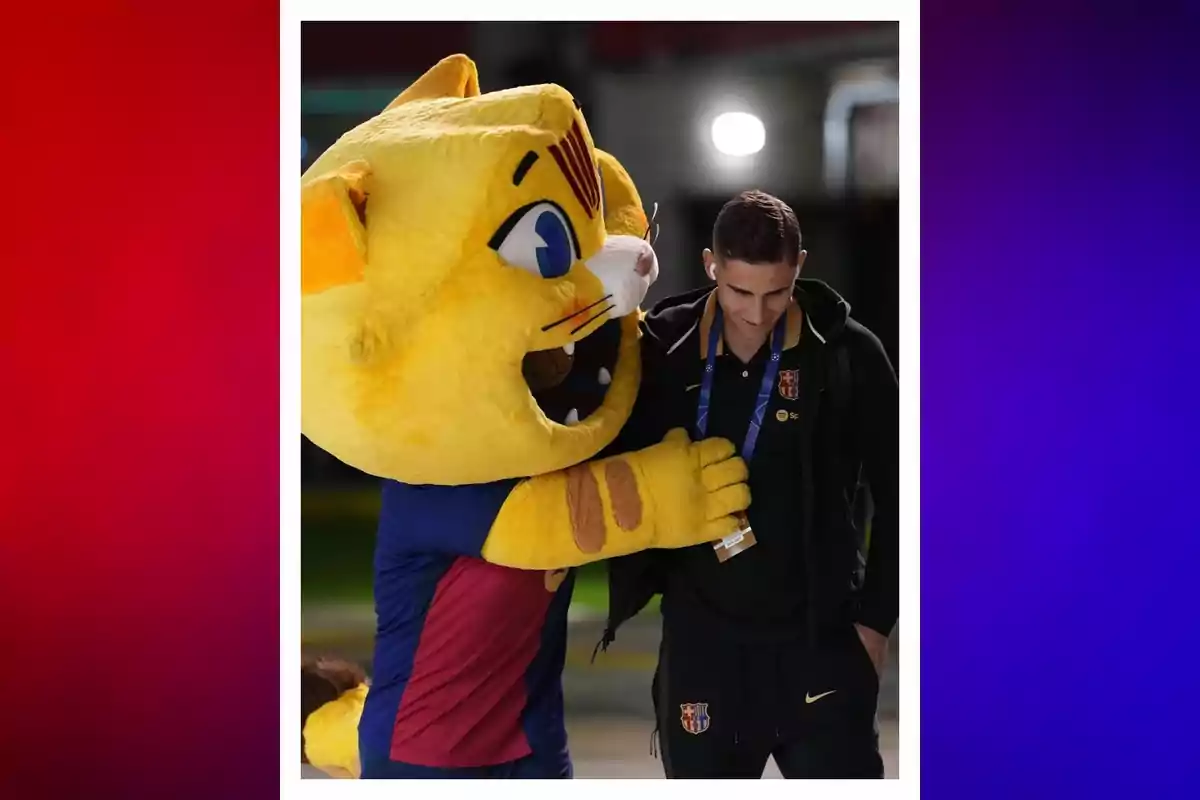Un home amb roba esportiva del Barcelona és abraçat per una botarga de gat groc amb samarreta del mateix equip. Un home amb roba esportiva del Barcelona és abraçat per una botarga de gat groc amb samarreta del mateix equip.