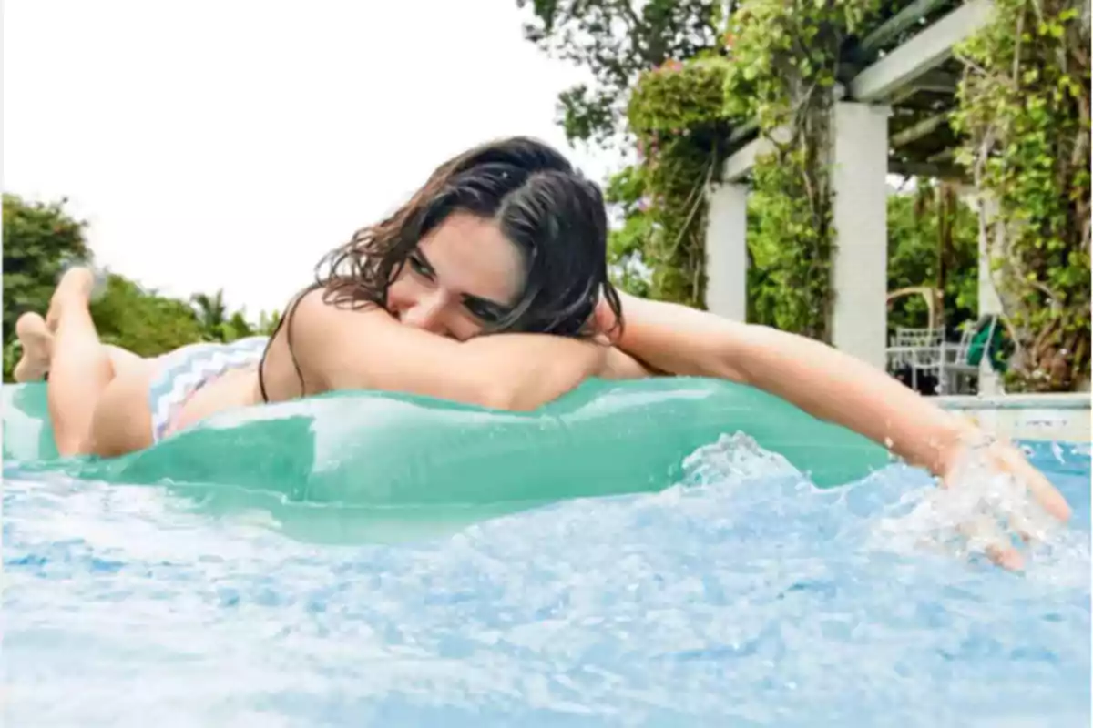 Dona estirada sobre un inflable verd en una piscina gaudint d’un dia assolellat Dona estirada sobre un inflable verd en una piscina gaudint d’un dia assolellat