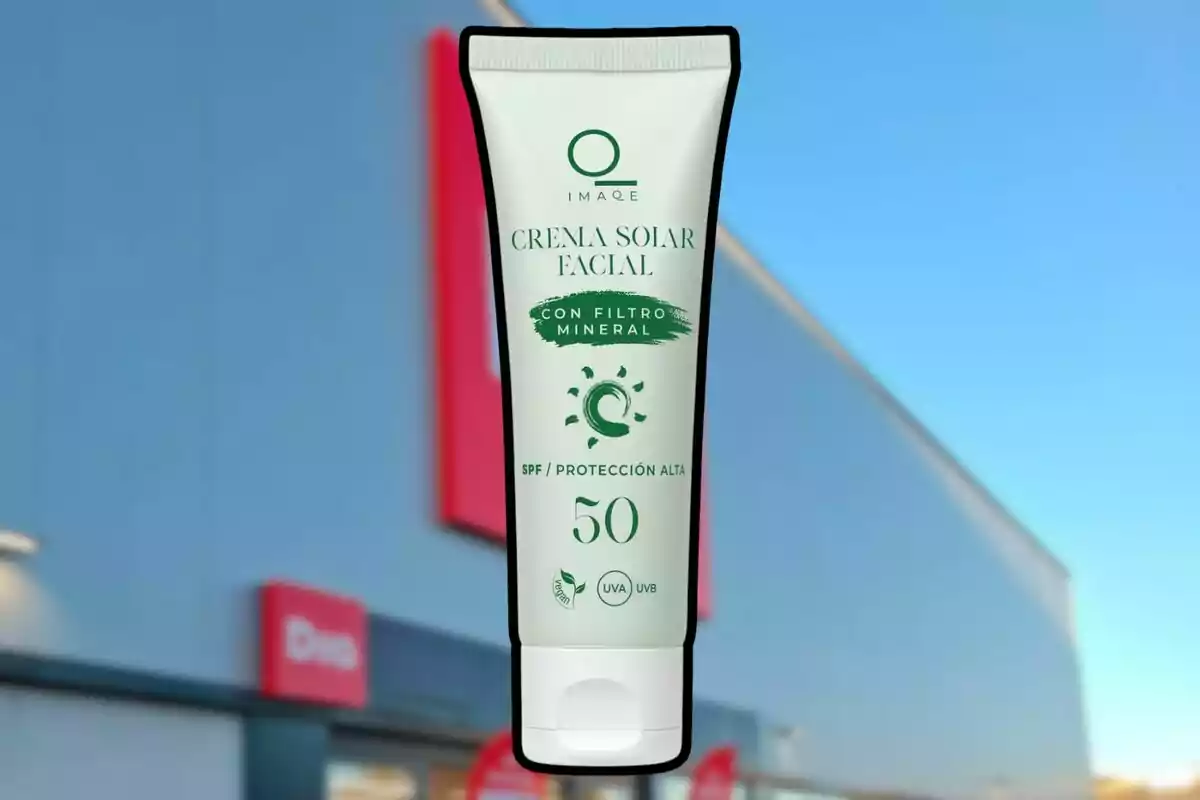 Envàs de crema solar facial amb filtre mineral SPF 50 sostingut davant d’una botiga amb façana blava i rètols vermells. Envàs de crema solar facial amb filtre mineral SPF 50 sostingut davant d’una botiga amb façana blava i rètols vermells.