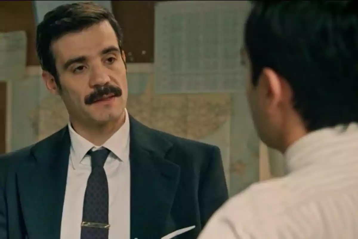 Javier Beltrán en una escena de 'Sueños de Libertad' amb bigoti i vestit fosc conversant amb una altra persona en una oficina. Javier Beltrán en una escena de 'Sueños de Libertad' amb bigoti i vestit fosc conversant amb una altra persona en una oficina.