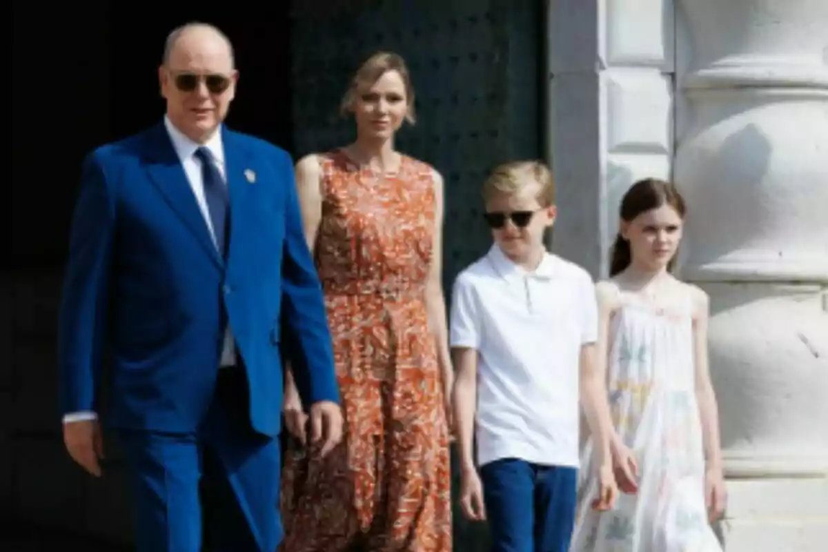 The Royal Family of Monaco, elegantly dressed, walk together outdoors in front of a white building. The Royal Family of Monaco, elegantly dressed, walk together outdoors in front of a white building.