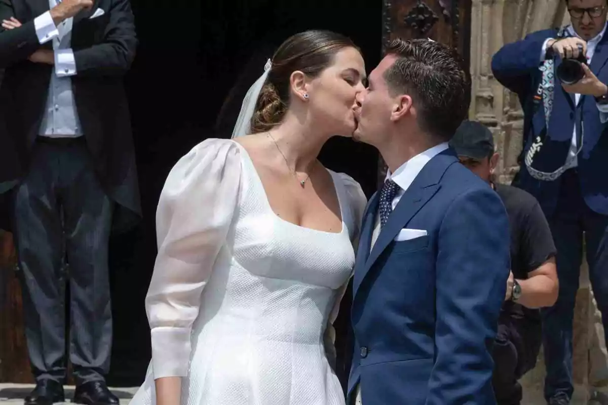 Chema Esteban i Lorena recent casats besant-se davant de l’església mentre un fotògraf captura el moment Chema Esteban i Lorena recent casats besant-se davant de l’església mentre un fotògraf captura el moment