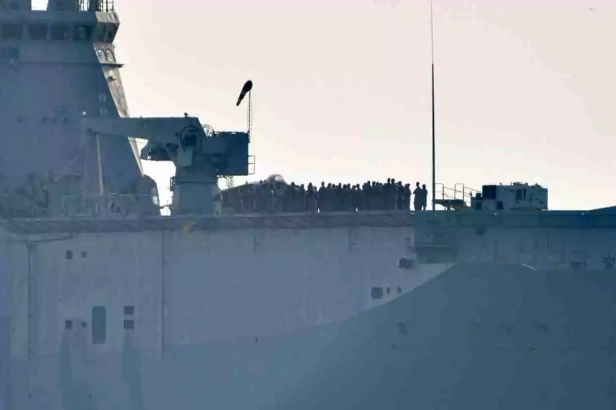 Un grupo de personas uniformadas se encuentra de pie sobre la cubierta de un gran buque gris en el mar Un grupo de personas uniformadas se encuentra de pie sobre la cubierta de un gran buque gris en el mar