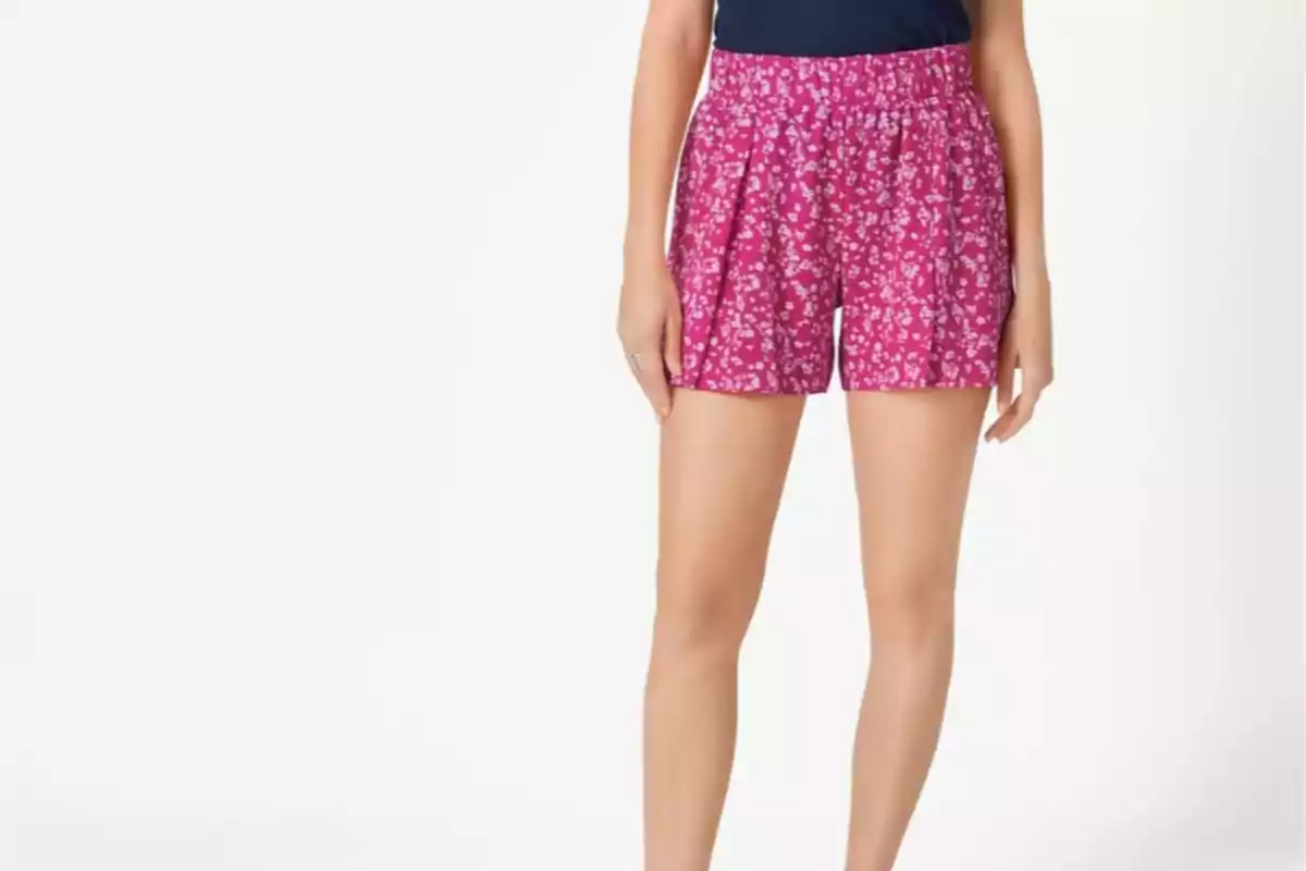 Mujer usando shorts rosas con estampado floral y blusa azul marino Mujer usando shorts rosas con estampado floral y blusa azul marino