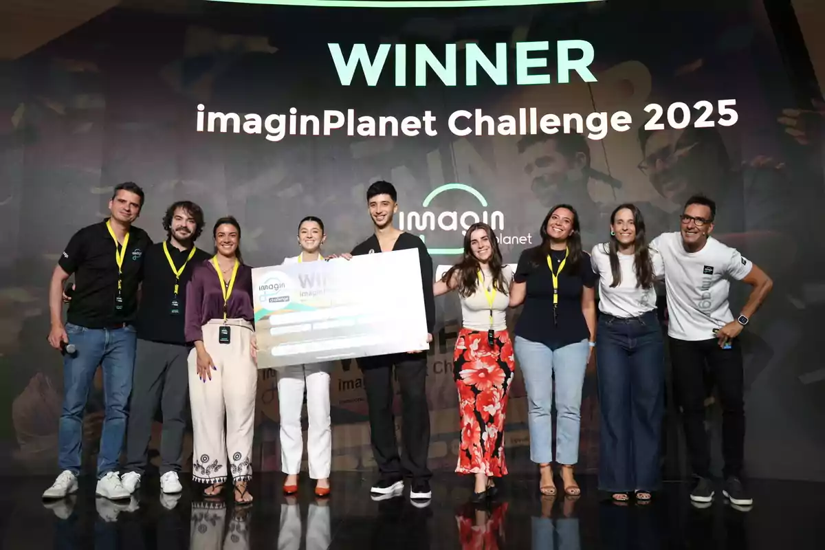 Grup de persones somrients posant a l’escenari amb un xec gegant com a guanyadors de l’imaginPlanet Challenge 2025 Grup de persones somrients posant a l’escenari amb un xec gegant com a guanyadors de l’imaginPlanet Challenge 2025