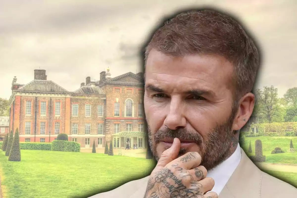Thoughtful man with a beard and tattoos on his hand in the foreground, with an old brick building and green gardens in the background