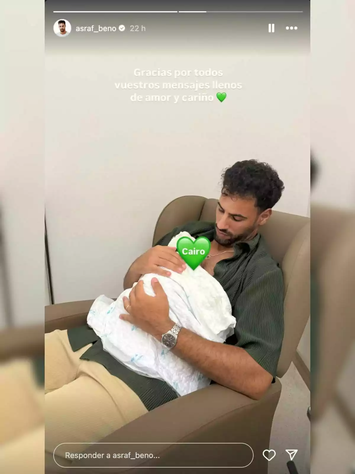 Home assegut en un sofà sostenint un nadó embolcallat amb una manta blanca, amb un emoji de cor verd que cobreix la cara del nadó i la paraula Cairo escrita a l’emoji. Home assegut en un sofà sostenint un nadó embolcallat amb una manta blanca, amb un emoji de cor verd que cobreix la cara del nadó i la paraula Cairo escrita a l’emoji.
