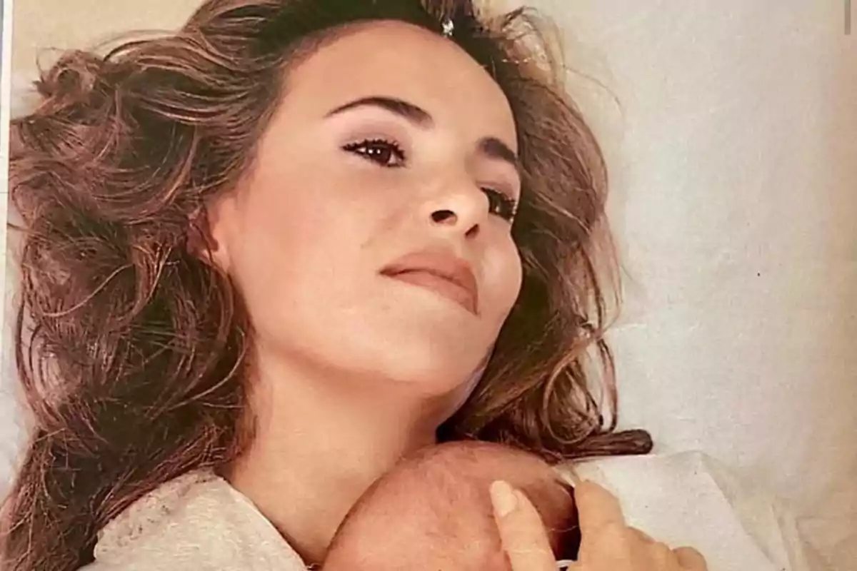 Dona ajaguda amb expressió serena sostenint un nadó en braços Dona ajaguda amb expressió serena sostenint un nadó en braços