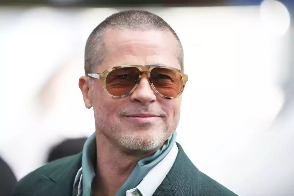 Man with large sunglasses and a green jacket smiles while looking at the camera Man with large sunglasses and a green jacket smiles while looking at the camera
