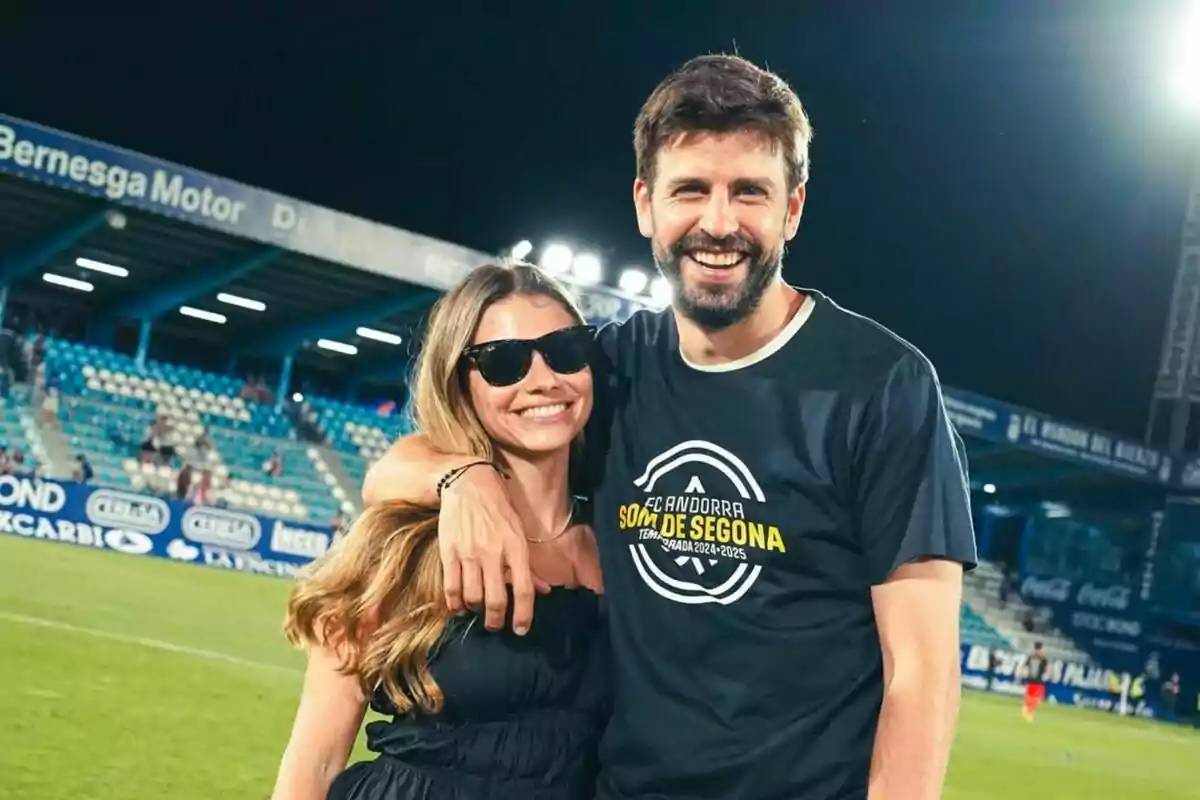 A couple smiles, hugging in a soccer stadium with blue stands and casual jerseys. A couple smiles, hugging in a soccer stadium with blue stands and casual jerseys.