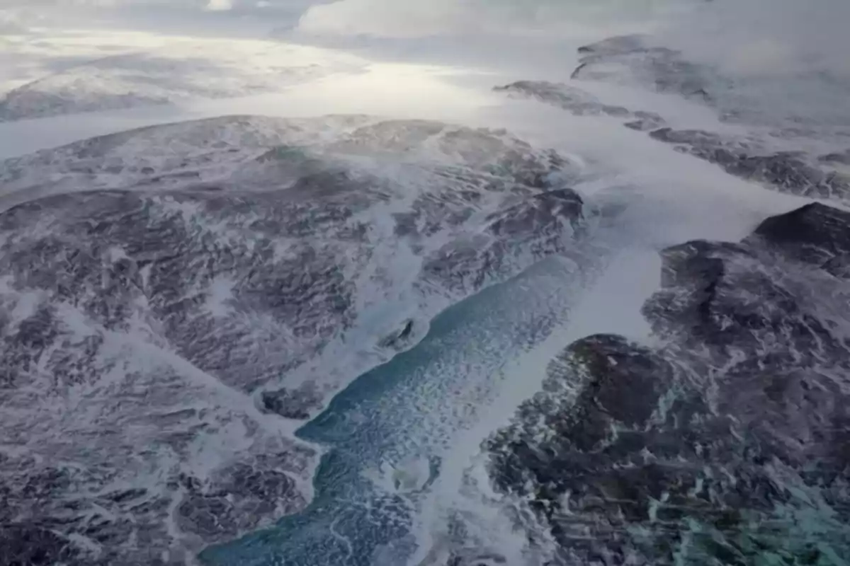 Aerial view of a landscape covered in snow and ice with mountains and a frozen river running through the valley of Greenland Aerial view of a landscape covered in snow and ice with mountains and a frozen river running through the valley of Greenland