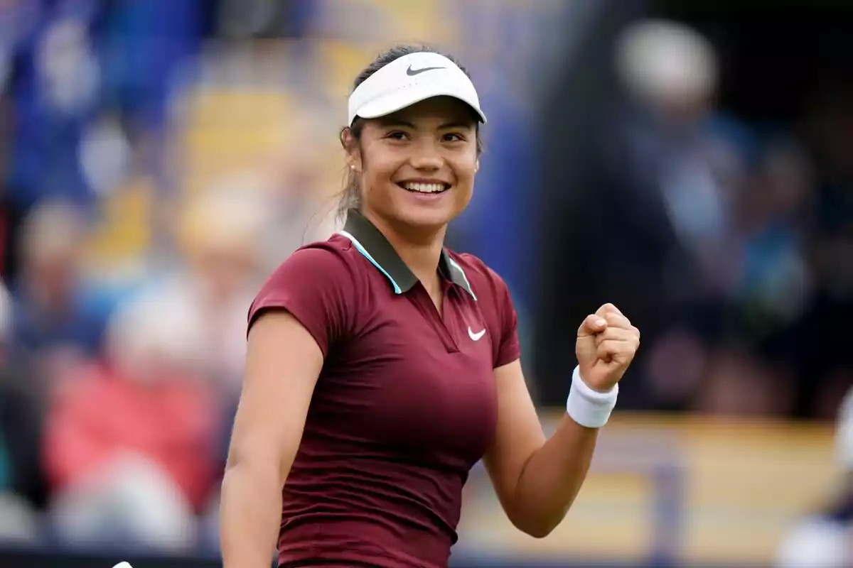 Smiling young tennis player celebrating on an outdoor court with a crowd in the background Smiling young tennis player celebrating on an outdoor court with a crowd in the background