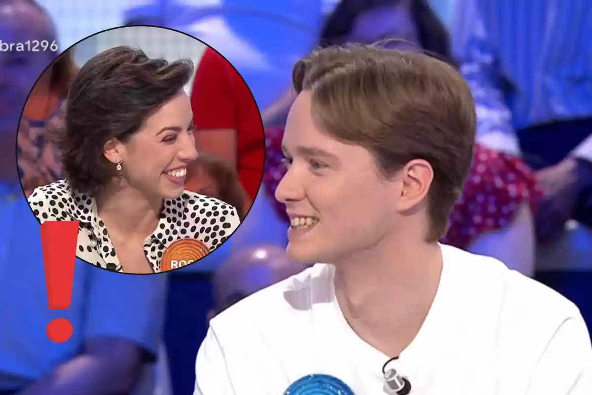 Dos concursants somriuen durant un programa de televisió amb una imatge circular que ressalta una dona i un signe d’exclamació vermell.