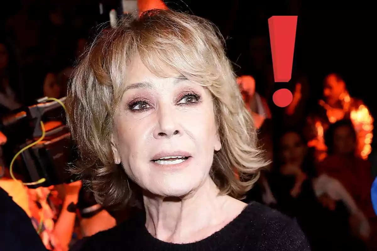 Dona de cabell ros curt amb expressió seriosa en un esdeveniment amb un signe d’exclamació vermell al fons
