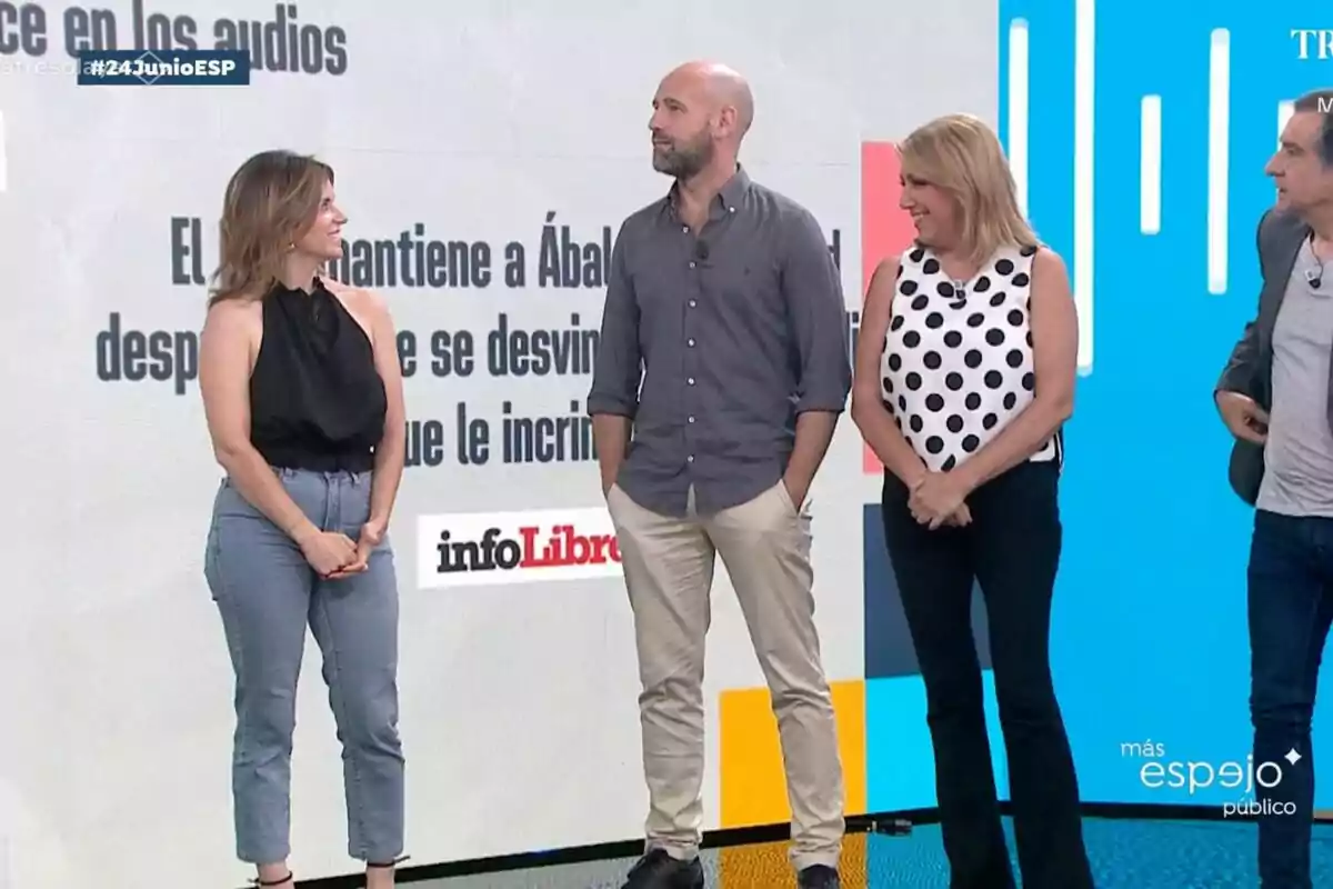 Four people standing and talking on the set of 'Espejo Público' with a digital background and news text. Four people standing and talking on the set of 'Espejo Público' with a digital background and news text.
