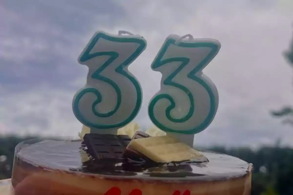 Pastís decorat amb espelmes en forma de número 33 i trossos de xocolata a sobre Pastís decorat amb espelmes en forma de número 33 i trossos de xocolata a sobre