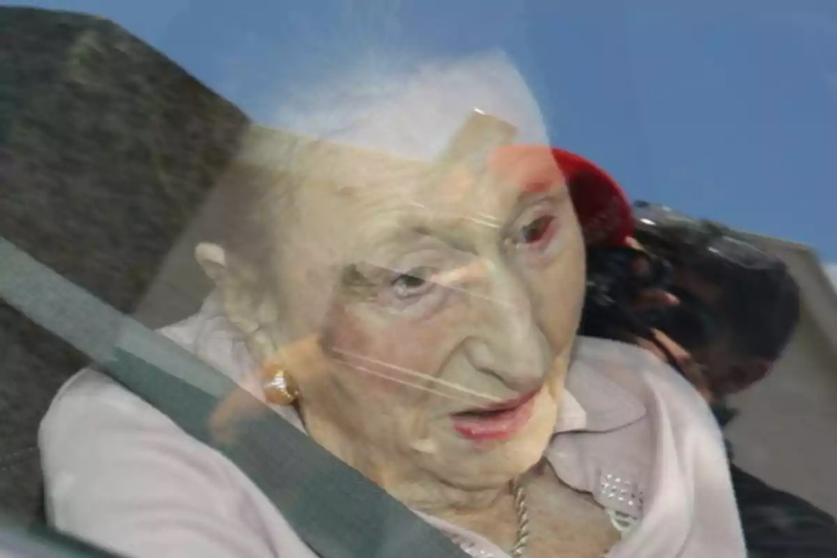 La infanta Margarida asseguda al seient d’un automòbil amb el cinturó de seguretat posat i el reflex d’una persona fent una foto a la finestra. La infanta Margarida asseguda al seient d’un automòbil amb el cinturó de seguretat posat i el reflex d’una persona fent una foto a la finestra.