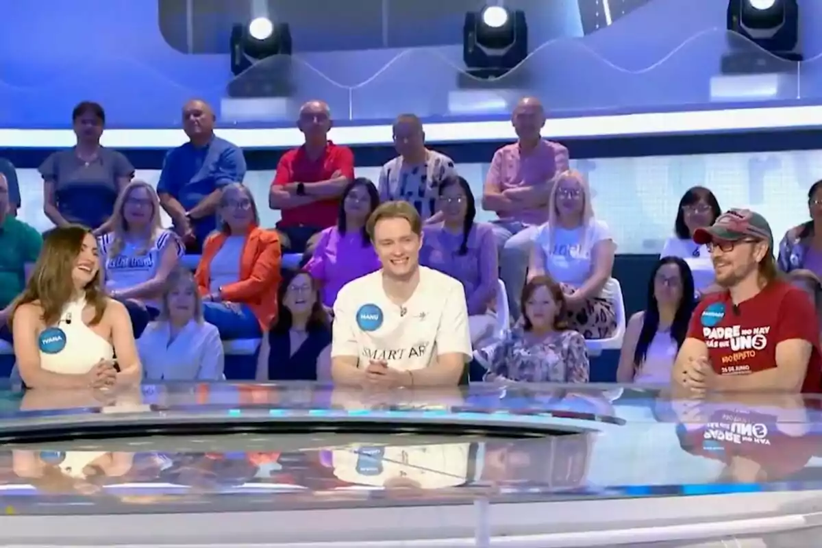 Tres concursants —un d’ells Manu Pascual— asseguts en una taula rodona somriuen mentre participen en un programa de televisió amb públic al fons. Tres concursants —un d’ells Manu Pascual— asseguts en una taula rodona somriuen mentre participen en un programa de televisió amb públic al fons.