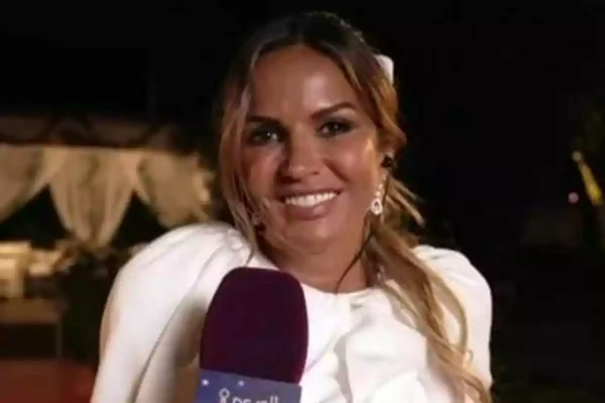 Marta López somrient amb un micròfon de De Divendres a la mà vestida de blanc en un esdeveniment nocturn a l’aire lliure Marta López somrient amb un micròfon de De Divendres a la mà vestida de blanc en un esdeveniment nocturn a l’aire lliure