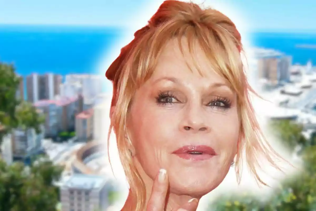 Melanie Griffith amb expressió pensativa en primer pla amb una ciutat costanera de Màlaga i el mar de fons desenfocats.