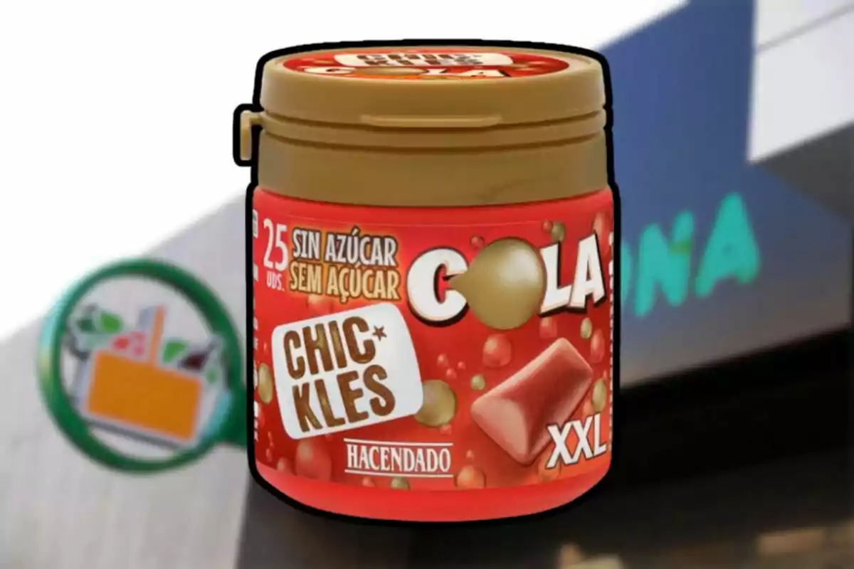 Envàs de xiclets sabor cola sense sucre de la marca Hacendado en mida XXL davant d’una botiga Mercadona desenfocada. Envàs de xiclets sabor cola sense sucre de la marca Hacendado en mida XXL davant d’una botiga Mercadona desenfocada.
