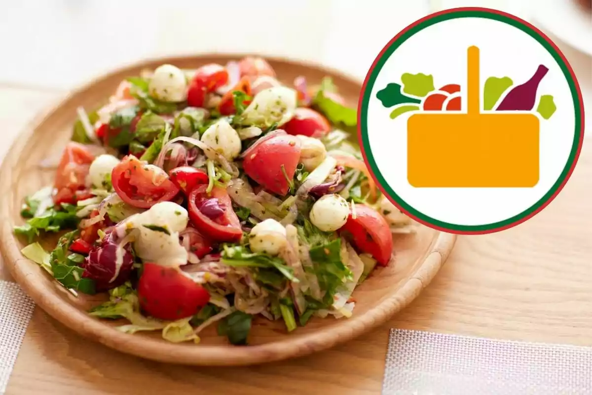 Amanida fresca amb tomàquets, formatge mozzarella i fulles verdes servida en un plat de fusta al costat d’una icona de cistell d’aliments Amanida fresca amb tomàquets, formatge mozzarella i fulles verdes servida en un plat de fusta al costat d’una icona de cistell d’aliments