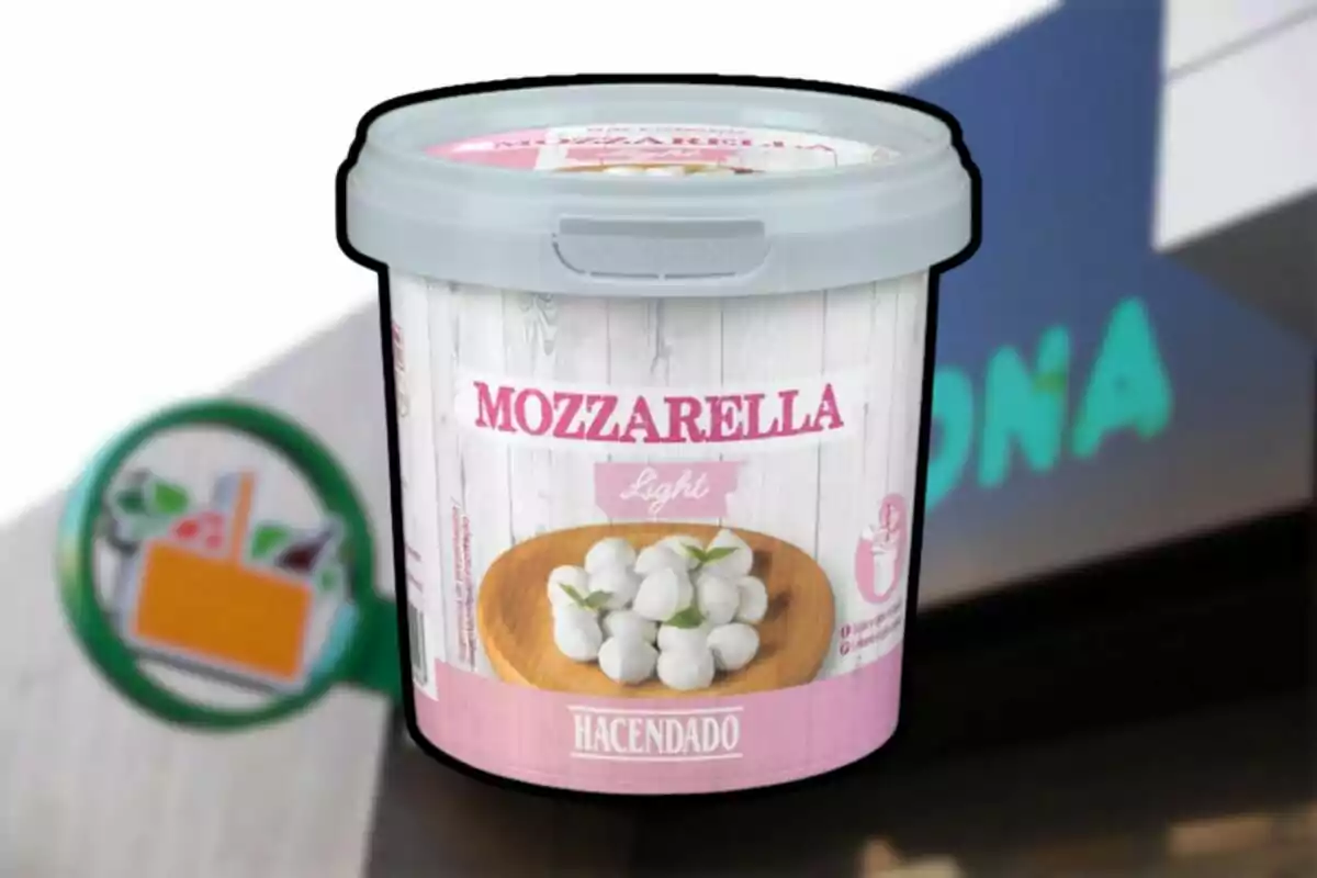 Envàs de mozzarella light de la marca Hacendado davant d’un cartell de supermercat desenfocat Envàs de mozzarella light de la marca Hacendado davant d’un cartell de supermercat desenfocat