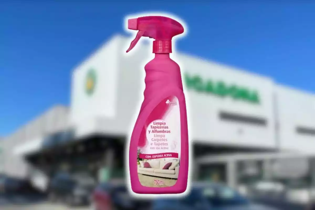 Ampolla de netejador rosa per a tapisseria i catifes de Mercadona davant d’una botiga amb façana blanca i lletres verdes desenfocades.