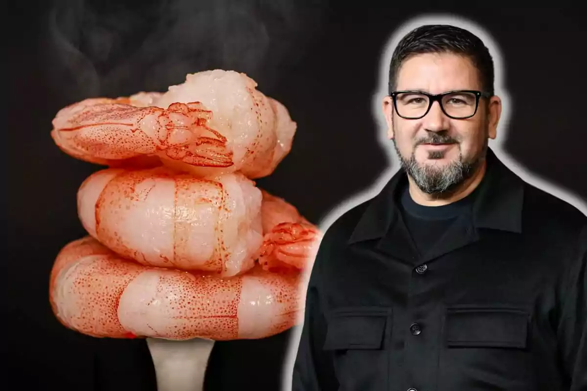 Man with glasses and a beard next to a pile of cooked shrimp against a dark background