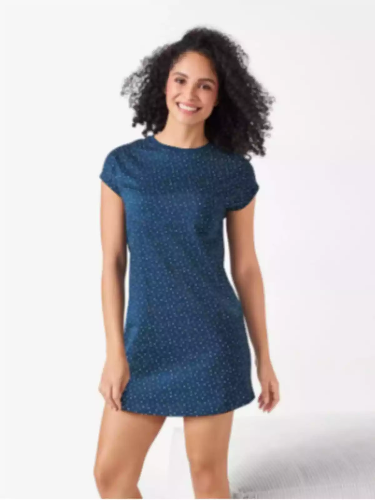 Dona jove amb cabells arrissats portant un vestit blau curt amb petits punts blancs i somrient davant d’un fons clar Dona jove amb cabells arrissats portant un vestit blau curt amb petits punts blancs i somrient davant d’un fons clar