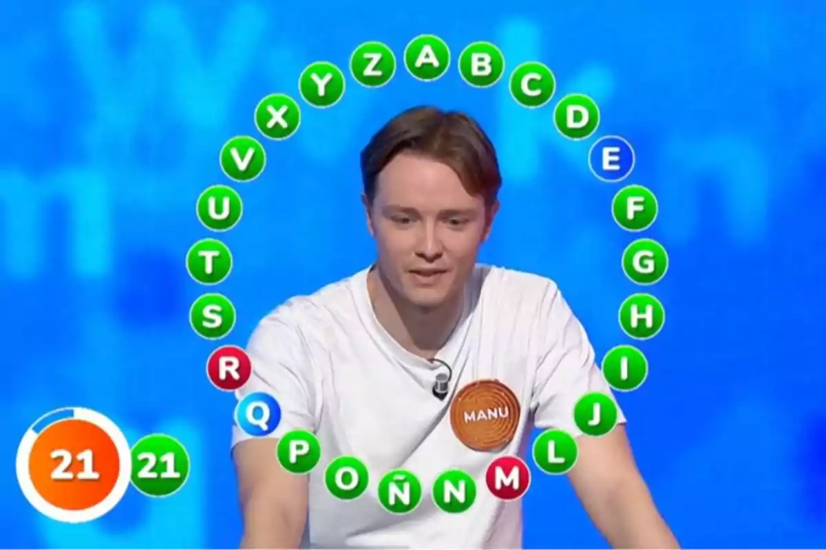 Manu participa a la prova final del rosco en un programa de televisió de preguntes i respostes amb lletres en cercle i un marcador de temps que mostra 21 segons. Captura de 'Pasapalabra' Manu participa a la prova final del rosco en un programa de televisió de preguntes i respostes amb lletres en cercle i un marcador de temps que mostra 21 segons. Captura de 'Pasapalabra'
