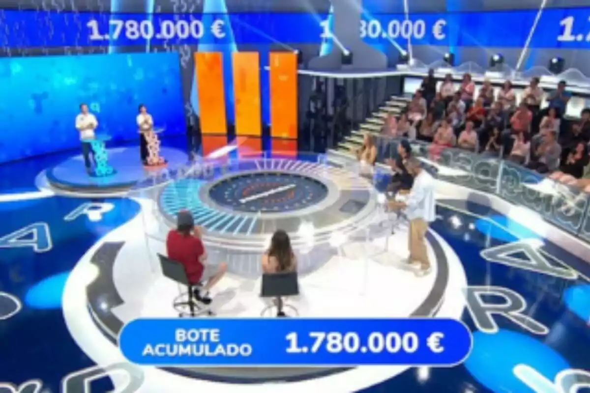 Plató de 'Pasapalabra' amb concursants, públic i un marcador que mostra un pot acumulat d’un milió set-cents vuitanta mil euros. Plató de 'Pasapalabra' amb concursants, públic i un marcador que mostra un pot acumulat d’un milió set-cents vuitanta mil euros.