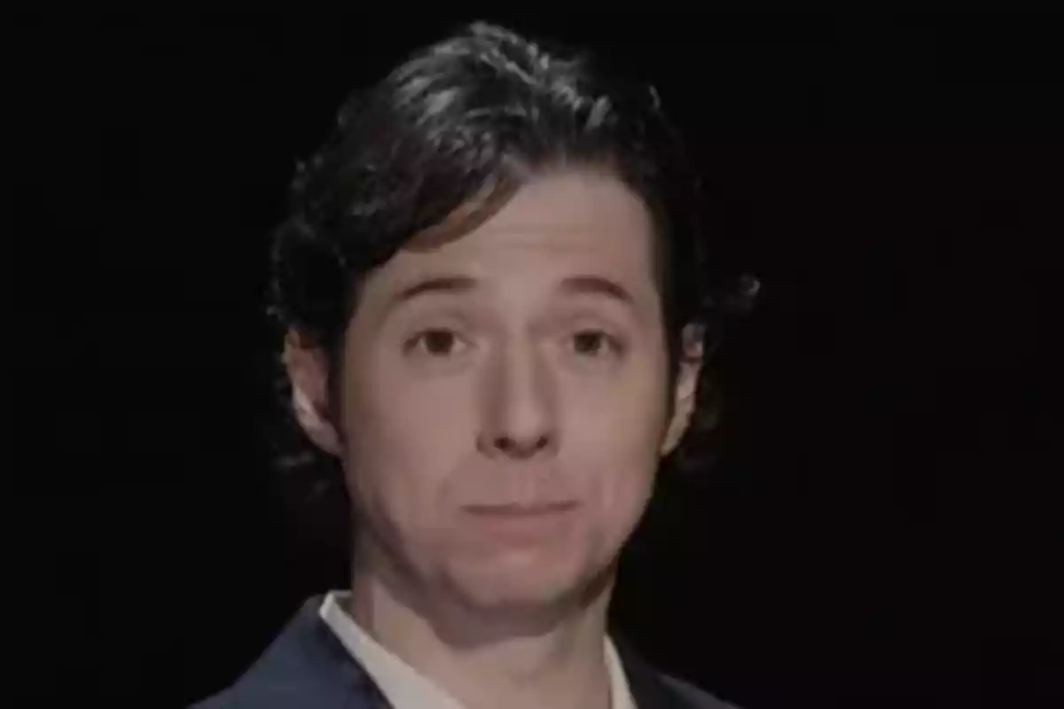 Álvaro Rojo amb expressió seriosa, vestint jaqueta fosca i camisa clara, fons negre. Álvaro Rojo amb expressió seriosa, vestint jaqueta fosca i camisa clara, fons negre.