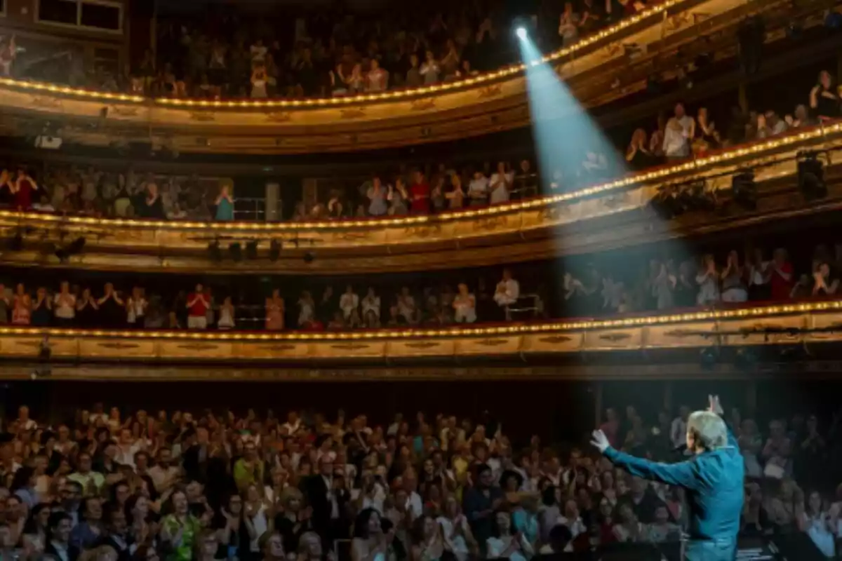 Raphael on stage in a theater full of applauding audience while a light shines on him. Raphael on stage in a theater full of applauding audience while a light shines on him.