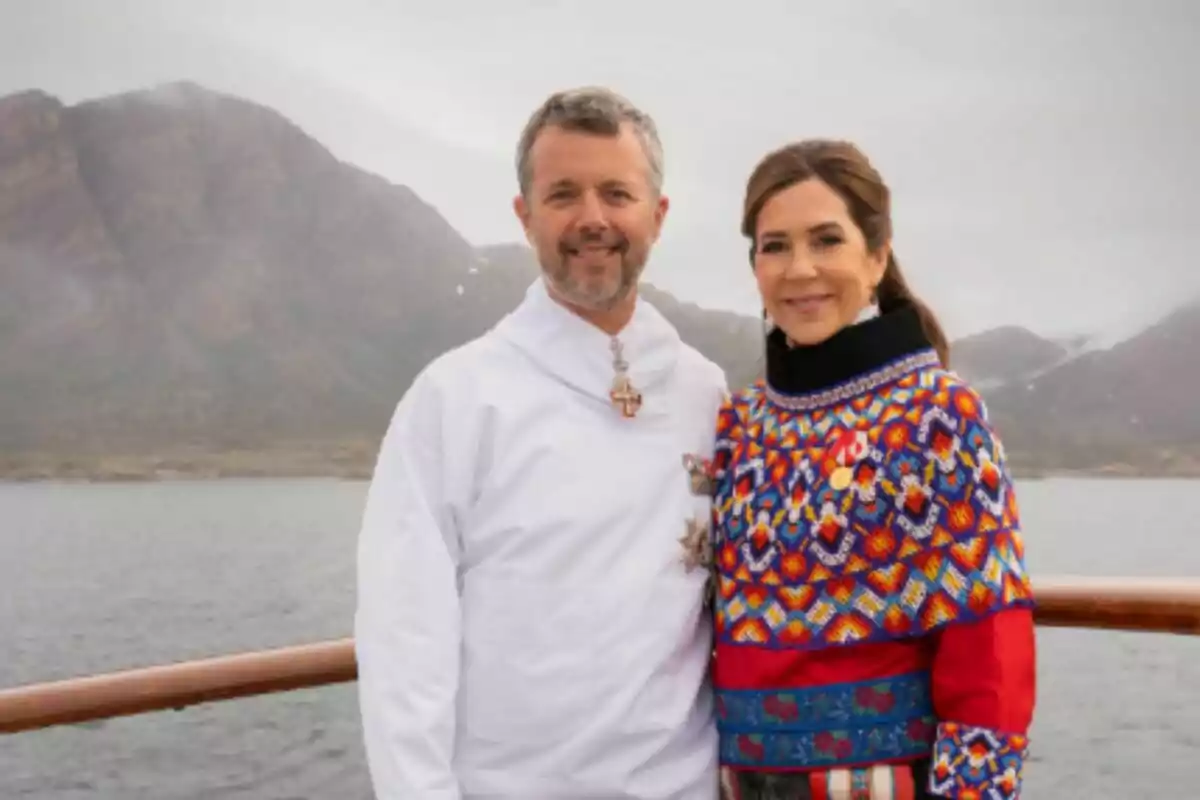 A couple—Federico and María of Denmark—posing in front of a mountainous landscape and a lake, both wearing colorful traditional clothing. A couple—Federico and María of Denmark—posing in front of a mountainous landscape and a lake, both wearing colorful traditional clothing.