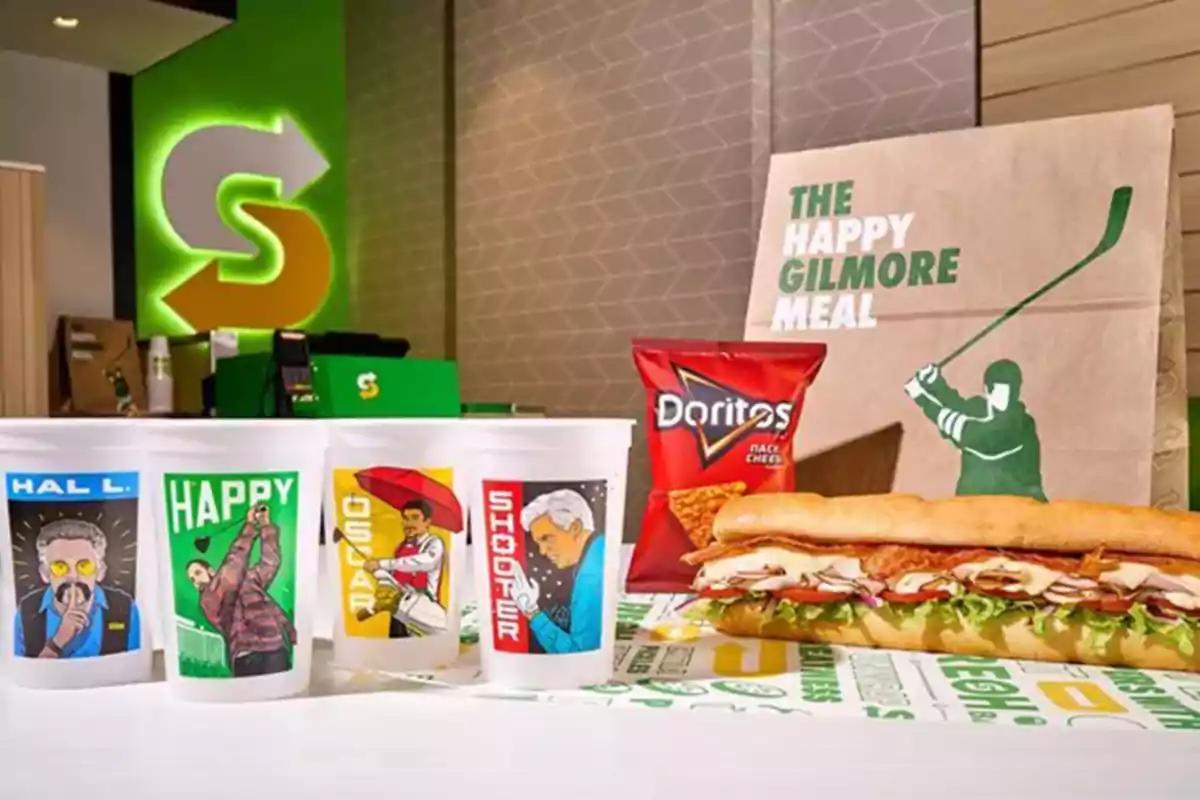 Subway combo called The Happy Gilmore Meal that includes a sandwich, a bag of Doritos, four cups with character illustrations, and a paper bag decorated with a golfer. Subway combo called The Happy Gilmore Meal that includes a sandwich, a bag of Doritos, four cups with character illustrations, and a paper bag decorated with a golfer.