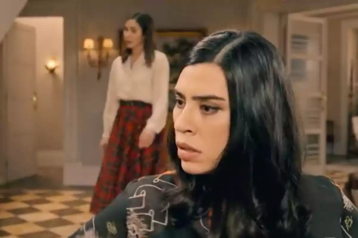 María en primer pla amb expressió seriosa mentre Begoña al fons camina en una habitació elegant. Captura de 'Sueños de libertad' María en primer pla amb expressió seriosa mentre Begoña al fons camina en una habitació elegant. Captura de 'Sueños de libertad'