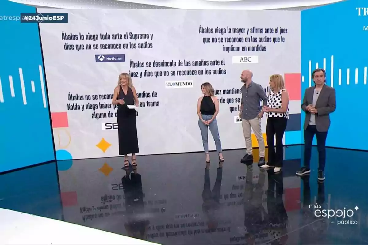 Five hosts of a television show are standing in a studio with a large screen in the background displaying news headlines about Ábalos and court audio recordings. Five hosts of a television show are standing in a studio with a large screen in the background displaying news headlines about Ábalos and court audio recordings.