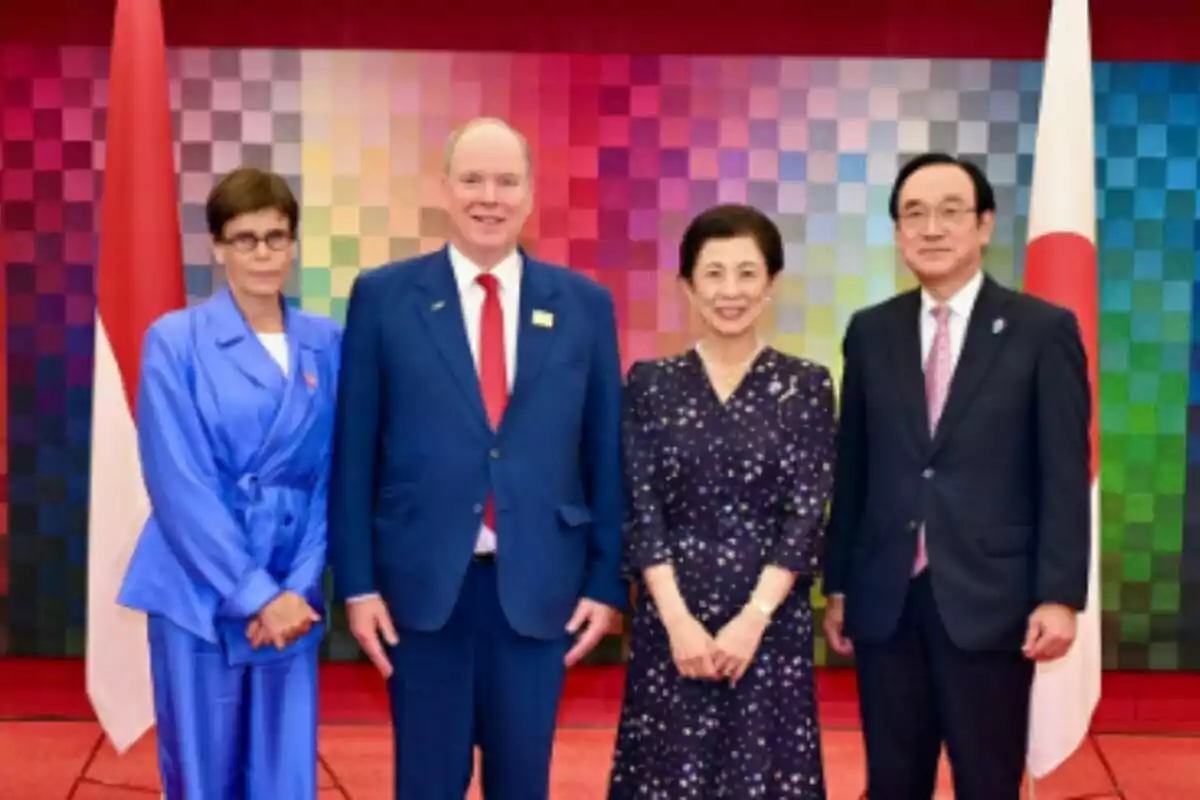 Quatre persones posen per a una foto formal —dues d'elles són l'Albert i l'Estefania de Mònaco— davant d'un fons colorit amb dues banderes als costats. Quatre persones posen per a una foto formal —dues d'elles són l'Albert i l'Estefania de Mònaco— davant d'un fons colorit amb dues banderes als costats.